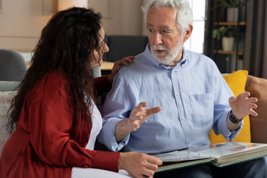 Woman talking with an older man as they look through a photo album at home