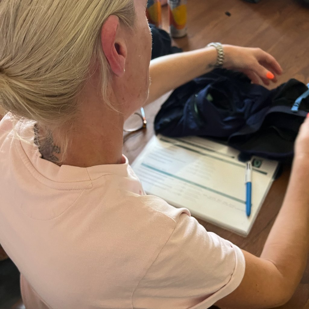 Woman in a pink T-shirt filling in a form at a table